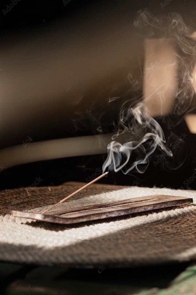 Bâton d’encens en train de brûler, dégageant une fumée fine dans une ambiance zen.