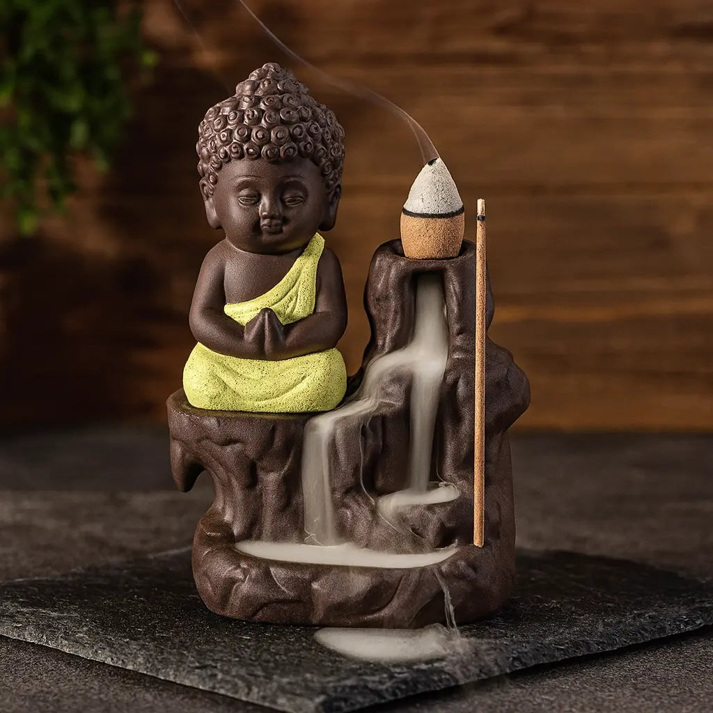 Brûleur d’encens Bouddha en céramique avec robe jaune et cascade à reflux sur fond bois et ardoise