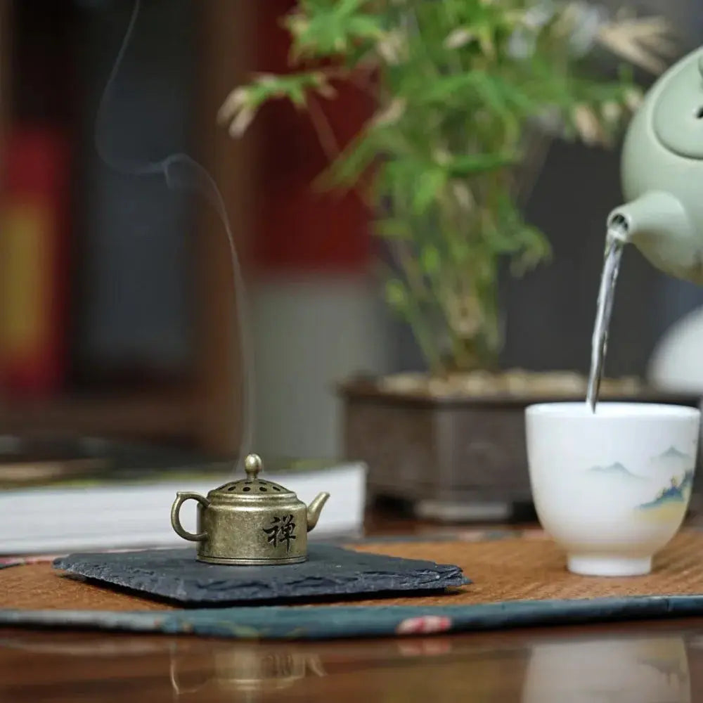 Brûleur encens théière en laiton mini avec un cône d’encens allumé.