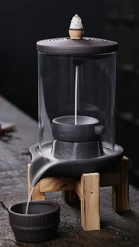 Fumée en cascade s’écoulant sur un porte-encens sculpté, posé sur une console décorative.