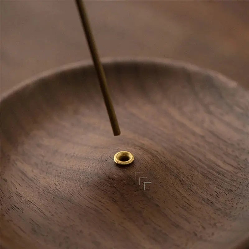 Porte-encens bâtons en noyer rond posé sur une table dans un décor zen.