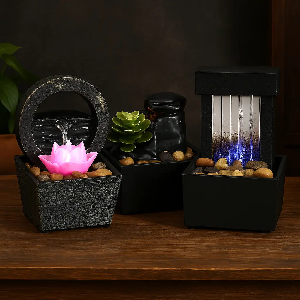 Trois fontaines décoratives de table avec lotus lumineux, cascade rocheuse et chute rectangulaire LED bleue, éclairées avec une luminosité équilibrée sur table bois.