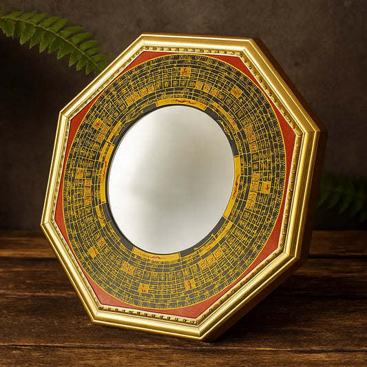 Miroir Feng Shui Bagua octogonal avec cadre doré et inscriptions traditionnelles noires et rouges, posé sur une table en bois sombre